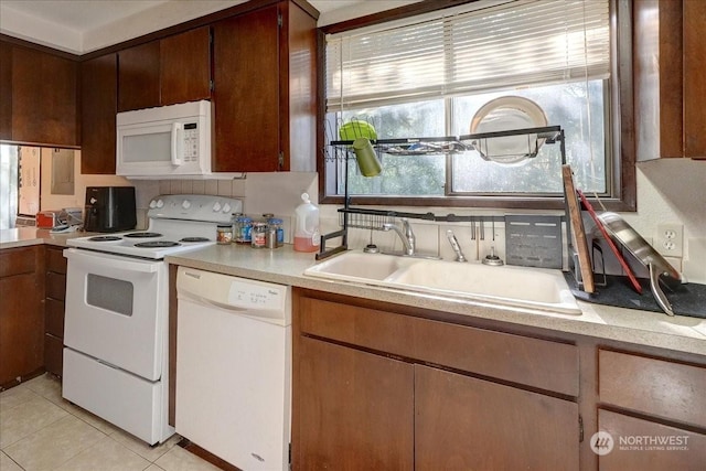 kitchen with light tile patterned floors, white appliances, light countertops, and a sink