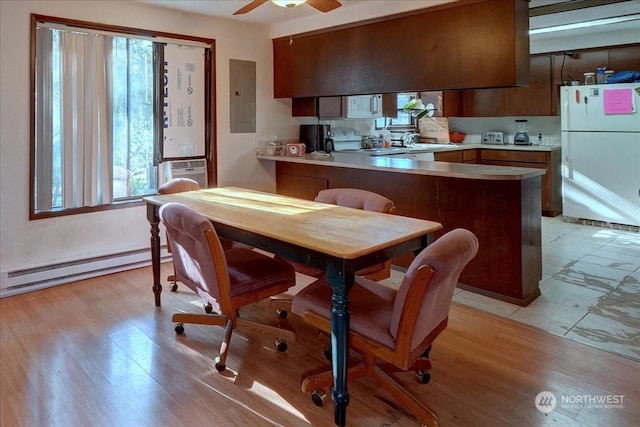 kitchen with kitchen peninsula, baseboard heating, ceiling fan, white fridge, and electric panel