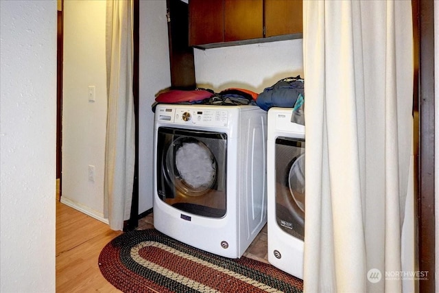 laundry room with washer and dryer, cabinet space, and light wood-style floors