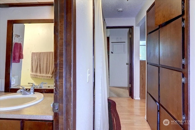 bathroom with a textured ceiling, vanity, and wood finished floors