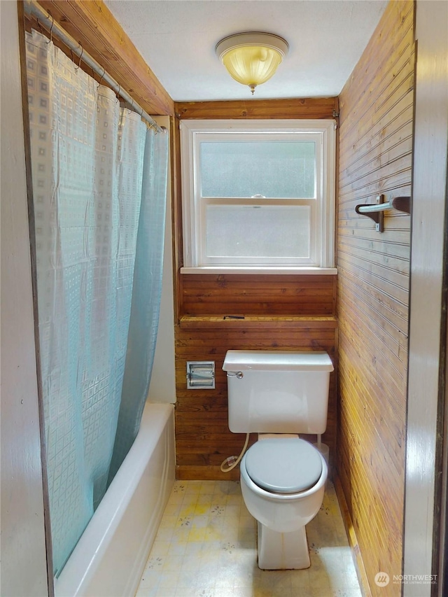 bathroom featuring wood walls, toilet, and shower / bath combination with curtain