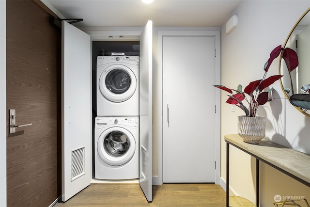 clothes washing area featuring light wood-type flooring and stacked washing maching and dryer