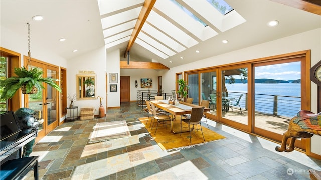 sunroom with lofted ceiling with skylight, french doors, and a water view