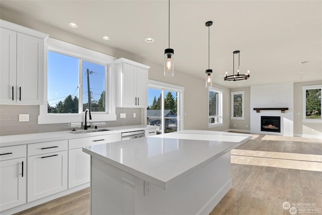 kitchen with white cabinets, a center island, a fireplace, and sink