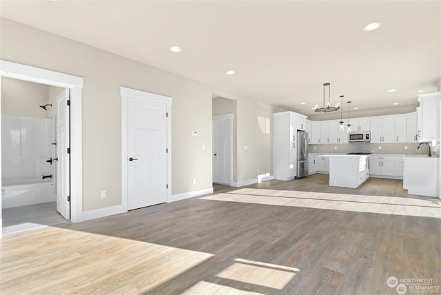 kitchen featuring pendant lighting, a center island, white cabinets, light hardwood / wood-style floors, and stainless steel appliances