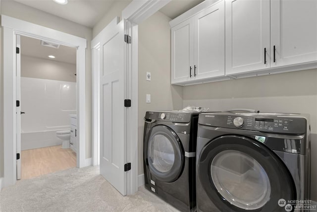 laundry area featuring cabinets, light carpet, and washer and clothes dryer