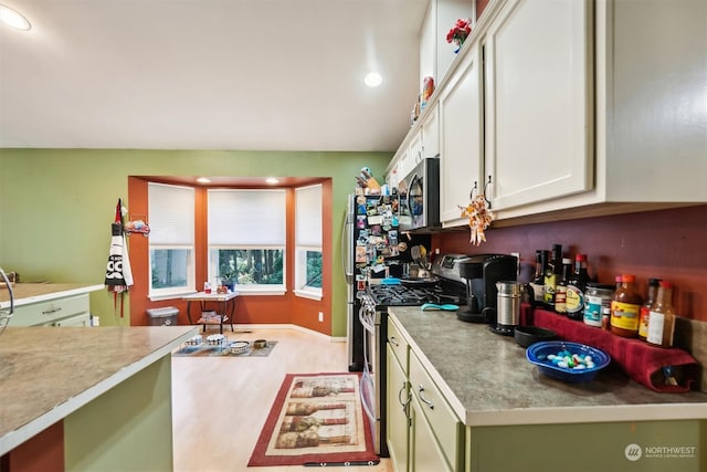 kitchen with green cabinets, white cabinetry, stainless steel appliances, and light wood-type flooring