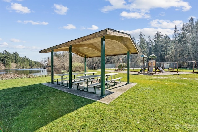 surrounding community with a playground, a yard, and a water view