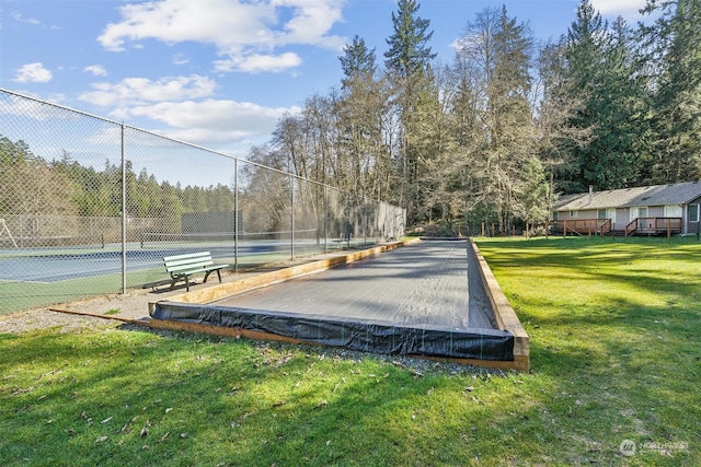 view of home's community featuring a lawn and tennis court