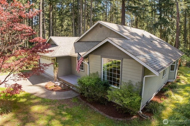 10405 Olympic Pl, Anderson Island, WA 98303 - view of front of house with concrete driveway, an attached garage, and roof with shingles