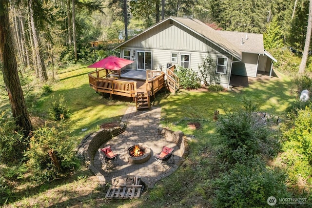 10405 Olympic Pl, Anderson Island, WA 98303 - back of property with a lawn, a deck, an outdoor fire pit, and a wooded view