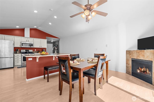 10405 Olympic Pl, Anderson Island, WA 98303 - dining room featuring recessed lighting, lofted ceiling, light wood-style flooring, a tiled fireplace, and ceiling fan