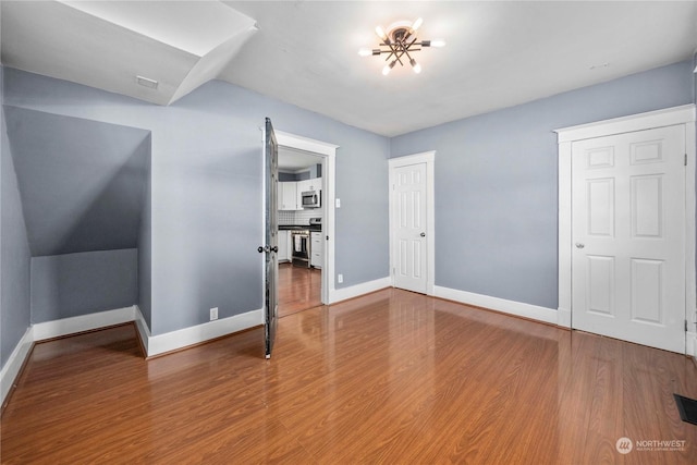 unfurnished bedroom featuring hardwood / wood-style floors and an inviting chandelier