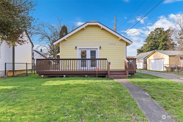 view of front of property featuring a wooden deck, a front yard, an outbuilding, and a garage