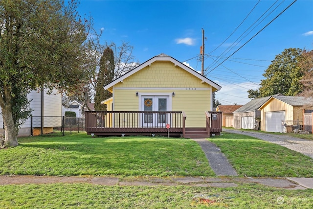 exterior space with a garage, a wooden deck, an outbuilding, and a front lawn