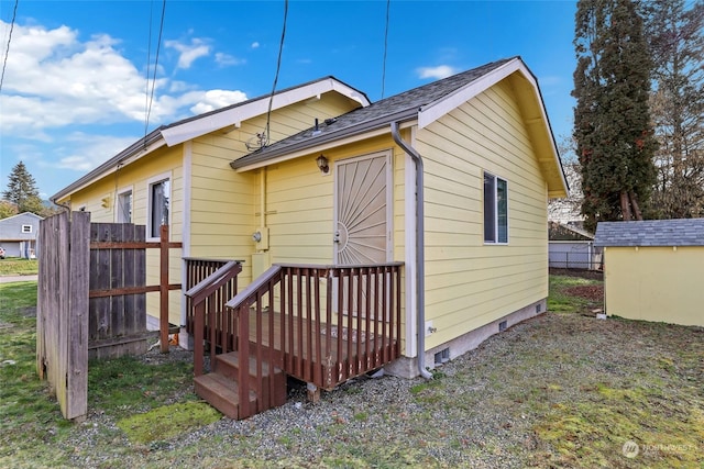 view of side of property featuring a deck and a storage unit