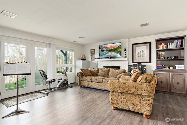 living room with dark hardwood / wood-style flooring, crown molding, and a brick fireplace