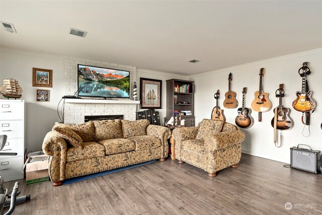 living room featuring wood-type flooring, crown molding, and a brick fireplace