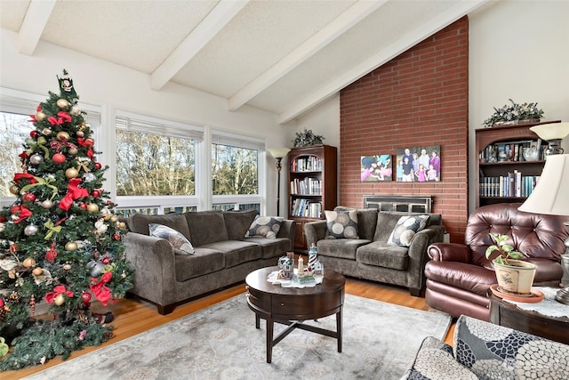 living room with a brick fireplace, vaulted ceiling with beams, and light hardwood / wood-style flooring