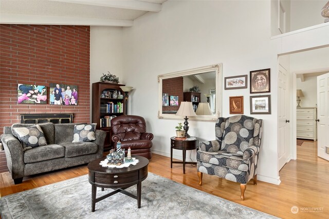 living room featuring a fireplace, beamed ceiling, high vaulted ceiling, and hardwood / wood-style flooring