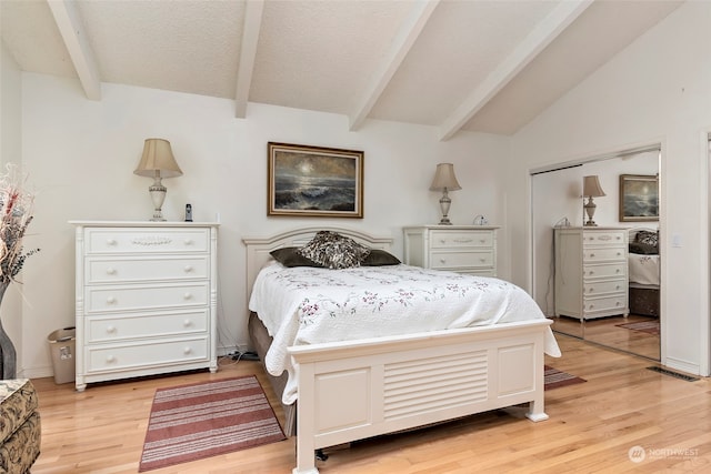 bedroom with a closet, lofted ceiling with beams, and light wood-type flooring