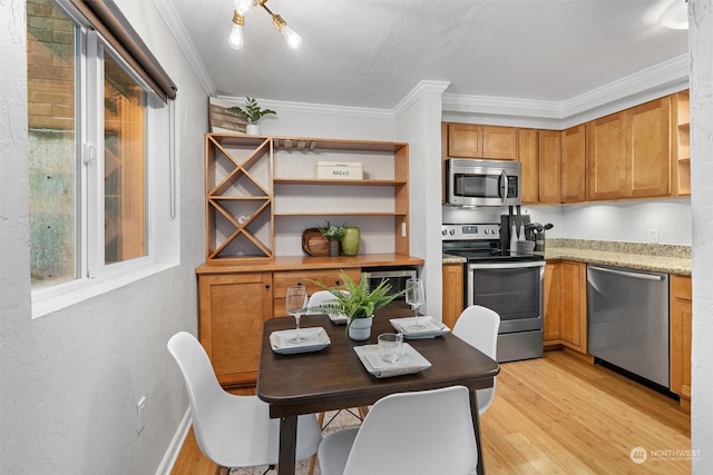 kitchen with appliances with stainless steel finishes, light hardwood / wood-style floors, light stone counters, and crown molding