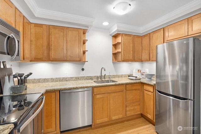 kitchen with light stone countertops, appliances with stainless steel finishes, ornamental molding, sink, and light hardwood / wood-style flooring