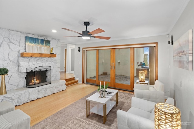 living room with hardwood / wood-style flooring, ceiling fan, crown molding, and a fireplace