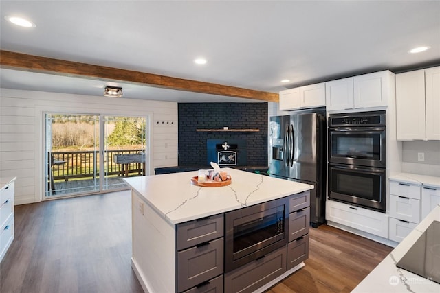 kitchen featuring a kitchen island, appliances with stainless steel finishes, white cabinetry, light stone counters, and dark wood-type flooring