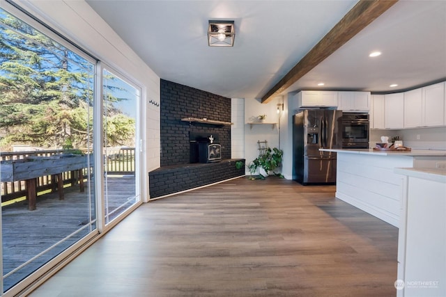 kitchen with stainless steel refrigerator with ice dispenser, hardwood / wood-style flooring, double wall oven, beamed ceiling, and white cabinets