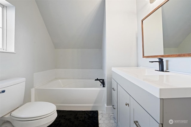 bathroom with vaulted ceiling, vanity, toilet, and a bathtub