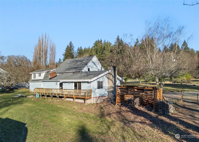 rear view of house featuring a wooden deck and a lawn