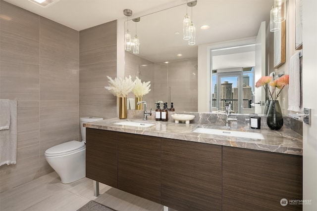 bathroom featuring tile patterned floors, vanity, toilet, and tile walls