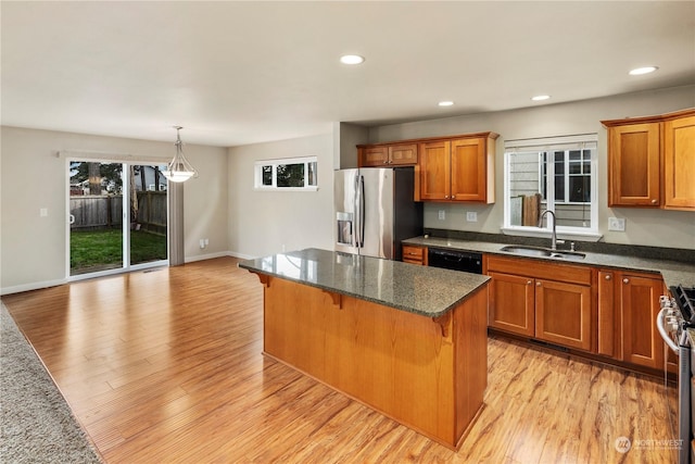 kitchen featuring hanging light fixtures, appliances with stainless steel finishes, sink, a kitchen bar, and a center island