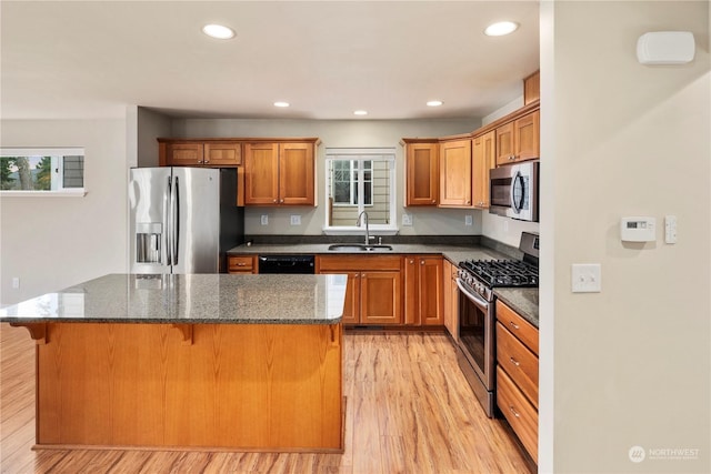 kitchen with sink, a kitchen breakfast bar, appliances with stainless steel finishes, and a kitchen island