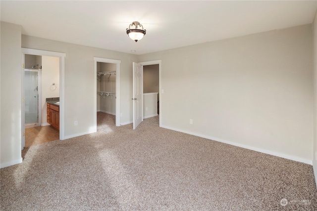 unfurnished bedroom featuring connected bathroom, a closet, and a walk in closet