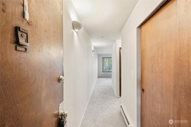 hallway with a baseboard heating unit and light carpet