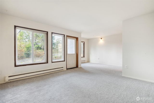 carpeted empty room featuring a baseboard heating unit