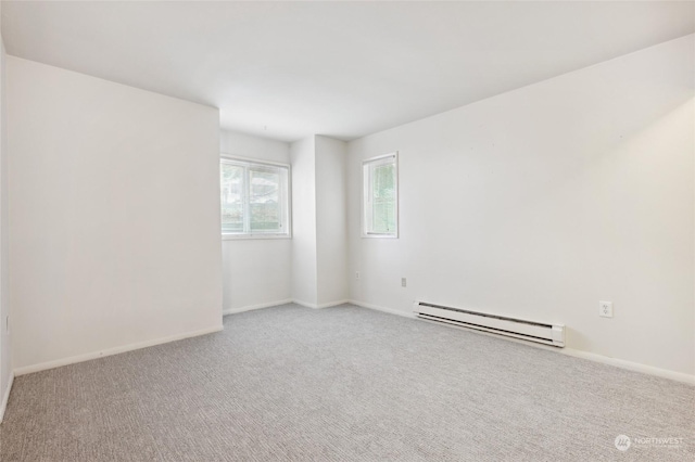 spare room featuring a baseboard heating unit and light colored carpet