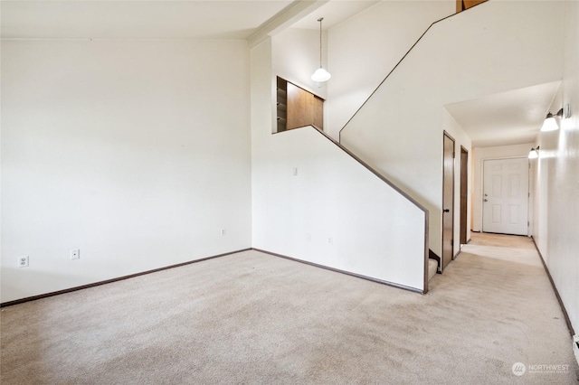 carpeted empty room with high vaulted ceiling