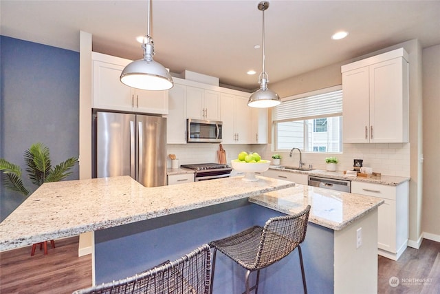 kitchen featuring white cabinetry, a kitchen island, pendant lighting, and appliances with stainless steel finishes