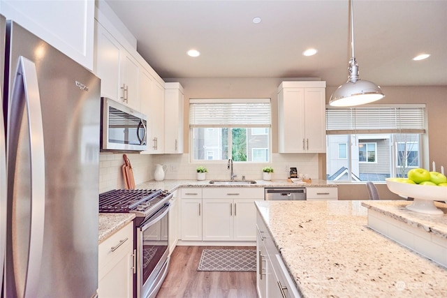 kitchen with white cabinets, sink, hanging light fixtures, and appliances with stainless steel finishes