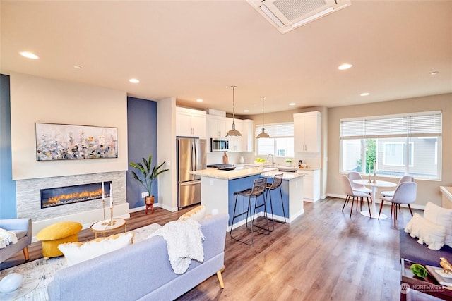 living room with a fireplace, light wood-type flooring, and sink