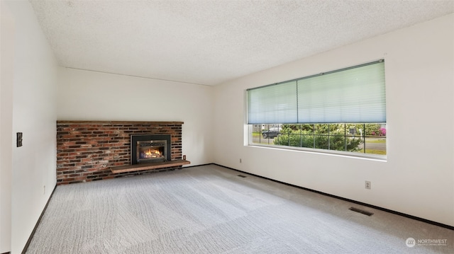 unfurnished living room featuring a brick fireplace, a textured ceiling, and carpet floors