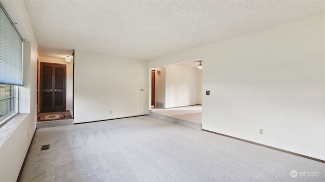 spare room with light colored carpet and a textured ceiling