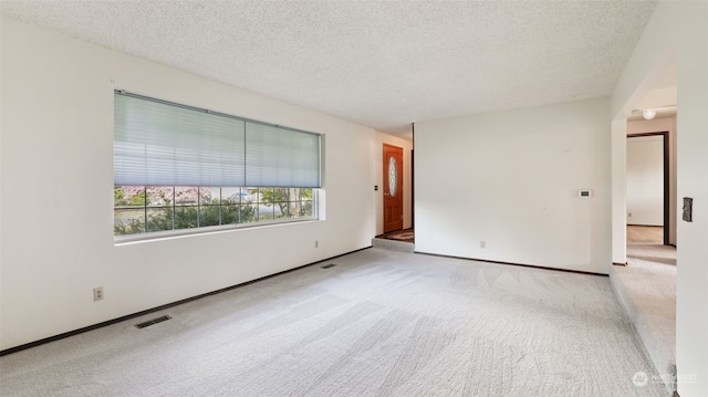 empty room featuring a textured ceiling and light carpet