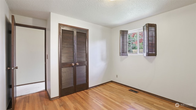 unfurnished bedroom featuring hardwood / wood-style flooring, a closet, and a textured ceiling