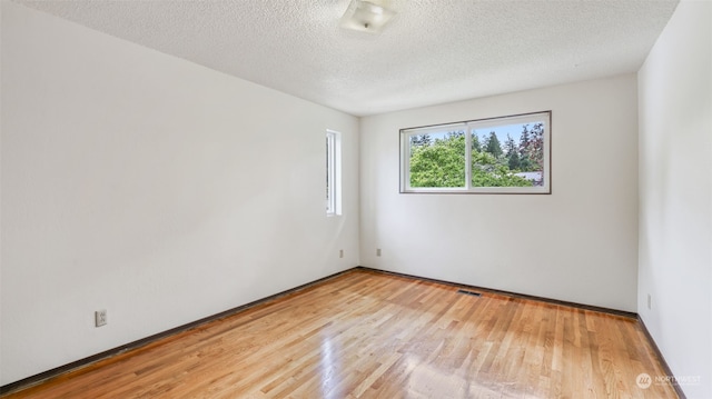 spare room featuring a textured ceiling and light hardwood / wood-style floors