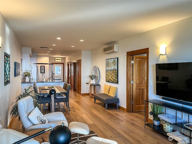 living room featuring a wall unit AC, light hardwood / wood-style flooring, and sink