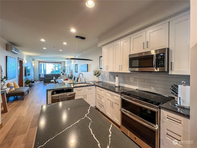 kitchen featuring white cabinets, stainless steel appliances, sink, backsplash, and a wall mounted AC